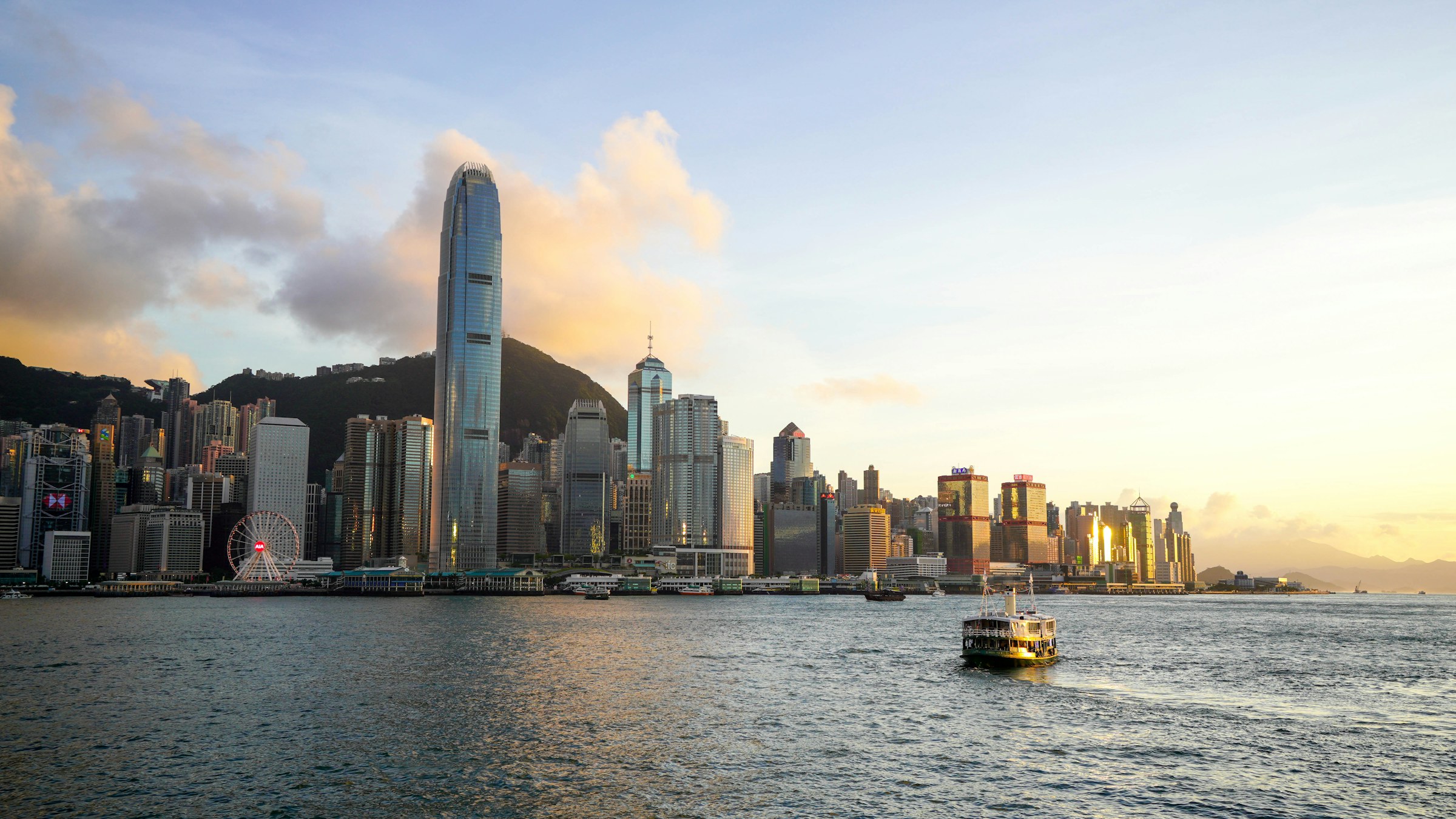 Victoria Harbour at golden hour, a Star Ferry crossing towards the Hong Kong Island skyline